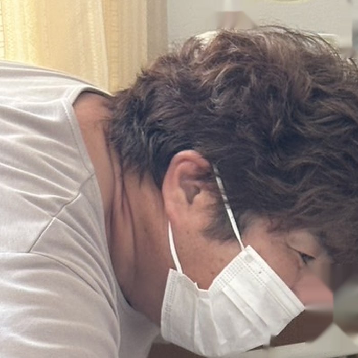 ご自宅で、管理者の安部五月が身をかがめて療養中の方に目線を合わせる様子